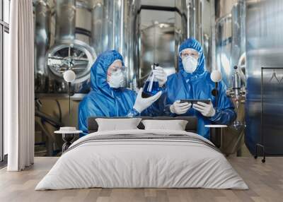 Two workers doing tests at chemical factory and wearing protective suits Wall mural