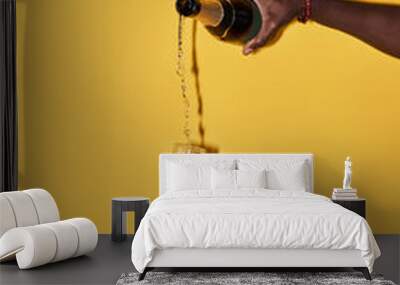 Vertical pop color concept of hands pouring champagne in glass on vibrant yellow background Wall mural