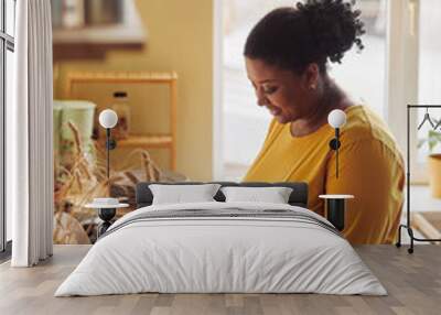 Vertical portrait of overweight black woman cooking healthy meal in kitchen lit by sunlight Wall mural