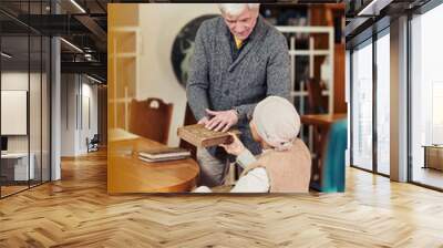 Vertical portrait of smiling senior professor helping young woman in wheelchair at college library Wall mural