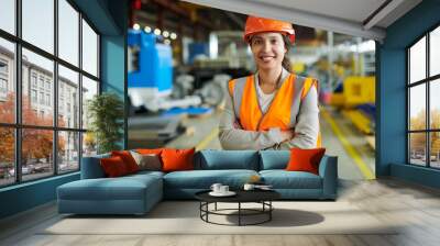 Waist up portrait of cheerful young woman wearing hardhat smiling happily looking at camera while posing confidently in production workshop, copy space Wall mural