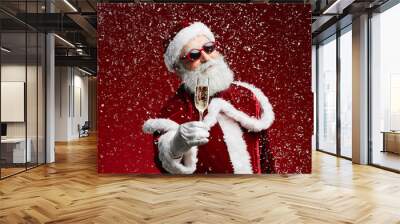 Waist up portrait of cool Santa holding champagne glass while standing over red background with snow falling, copy space Wall mural