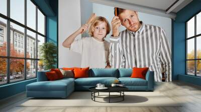 Waist up portrait of father and son brushing hair in minimal home interior and getting dressed Wall mural