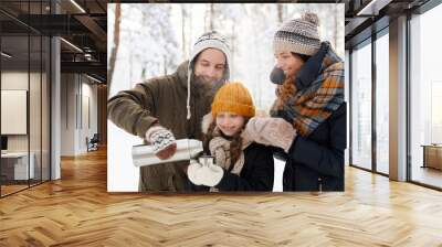 Waist up portrait of happy family drinking hot tea in winter forest, copy space Wall mural