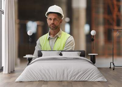 Waist up portrait of mature construction worker looking at camera while standing with arms crossed at construction site, copy space Wall mural