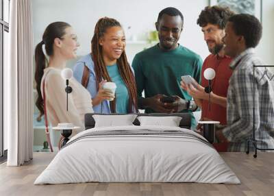 Waist up portrait of multi-ethnic group of people dressed in casual wear and laughing cheerfully while chatting in office Wall mural