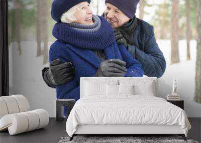 Waist up portrait of playful senior couple enjoying walk in winter forest Wall mural