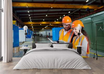 Waist up portrait of smiling female factory worker using digital tablet while discussing production with foreman in workshop, copy space Wall mural