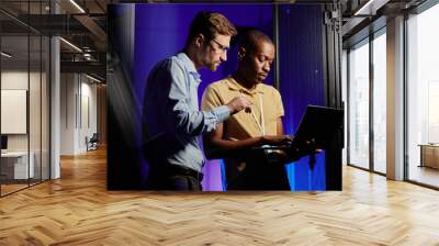 Waist up portrait of two network engineers using computer in dark server room lit by neon light, copy space Wall mural