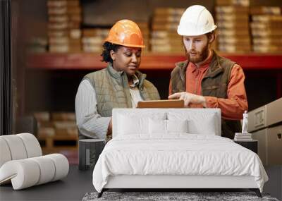 Waist up portrait of two workers wearing hardhats in factory warehouse and using digital tablet Wall mural