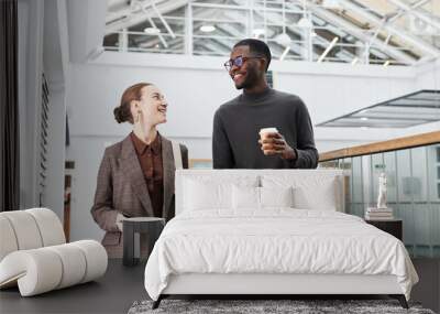 Waist up portrait of two young business people walking towards camera in office building while starting work in morning, copy space Wall mural