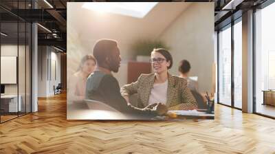 Warm toned portrait of two business people chatting in cafe during coffee break, copy space Wall mural