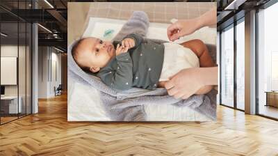 Warm-toned portrait of unrecognizable mother dressing cute mixed-race baby on changing table, copy space Wall mural