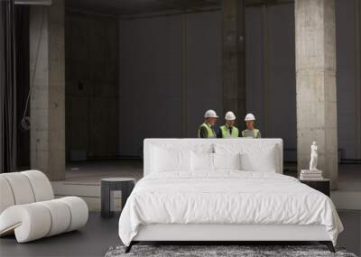 Wide angle portrait of business people wearing hardhats and holding plans while standing at construction site indoors, copy space Wall mural