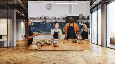 Wide angle view at female chef instructing people during cooking class in kitchen, copy space Wall mural