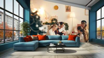 Wide angle view at modern young people celebrating Christmas sitting at dinner table in elegant dining room, copy space Wall mural