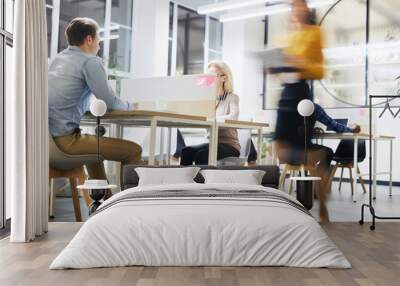 Work lifestyle in modern office: busy people working at tables in open space office, blurred motion of business lady Wall mural