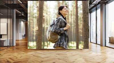 Young girl with backpack enjoying her hiking in the forest in summer Wall mural