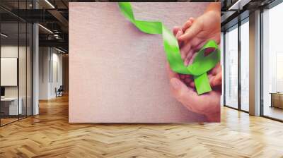 Adult and child hands holding Lime Green Ribbon, panoramic banner background, Mental health awareness and Lymphoma Awareness Wall mural