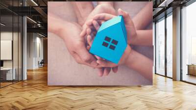 Adult and child hands holding white house, family home and homeless shelter, social distancing concept Wall mural