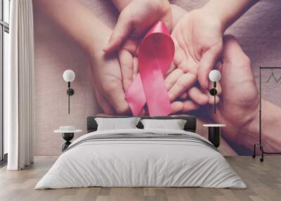 Family hands holding pink ribbon, breast cancer awareness, October pink concept Wall mural