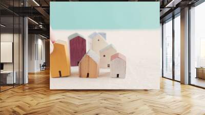 Hand choosing yellow miniature house, searching perfect property in high demand housing boom, choosing best house insurance, making right decision on home investment concept Wall mural