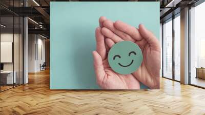 Hands holding green happy smile face paper cut, good feedback rating,positive customer review, experience, satisfaction survey ,mental health assessment, child wellness,world mental health day concept Wall mural