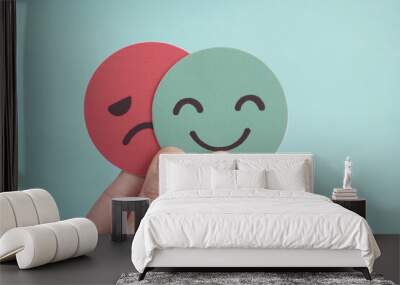 hands holding sad face hiding behind happy face, bipolar and depression, mental health, split person Wall mural