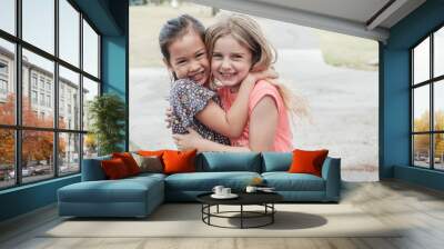 Happy and healthy mixed race multiethnic young little girls hugging and smiling in the park, best friend kids and children friendship, equality, positive mental health wellness concept Wall mural