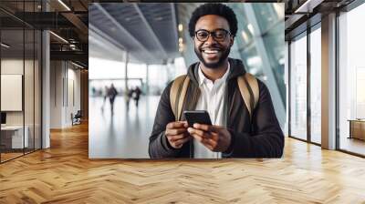 Handsome smiling African American young man wearing glasses with digital tablet looking at camera at airport Wall mural