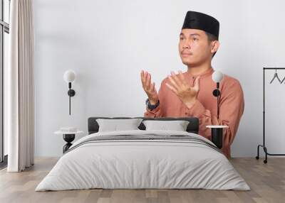 Portrait of Asian Muslim man praying with open arm isolated over white background Wall mural