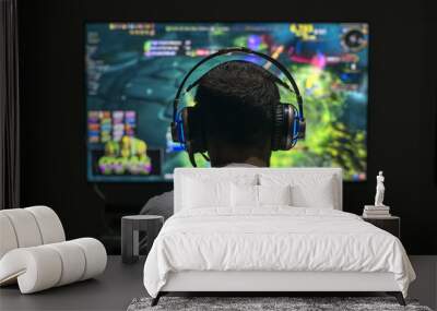 young gamer playing video game wearing headphone. Wall mural