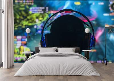 Young gamer playing video game wearing headphone. Wall mural