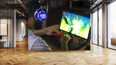 Young gamer playing video game wearing headphone. Wall mural