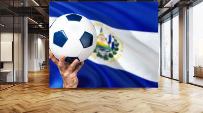 El Salvador soccer concept. National team player hand holding soccer ball with country flag background. Copy space for text. Wall mural