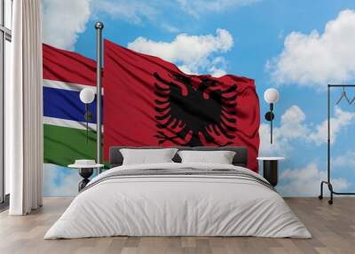 Gambia and Albania flag waving in the wind against white cloudy blue sky together. Diplomacy concept, international relations. Wall mural