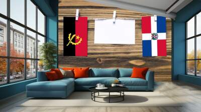 Hanging flags of Angola and Dominican Republic attached to rope with clothes pins with copy space on white note paper on wooden background.Diplomatic relations between countries. Wall mural