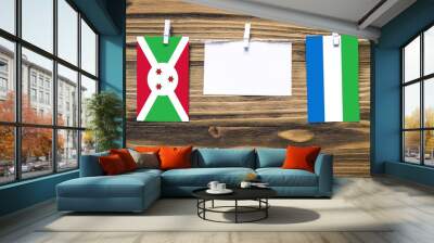 Hanging flags of Burundi and Sierra Leone attached to rope with clothes pins with copy space on white note paper on wooden background.Diplomatic relations between countries. Wall mural