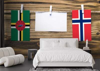 Hanging flags of Dominica and Norway attached to rope with clothes pins with copy space on white note paper on wooden background.Diplomatic relations between countries. Wall mural