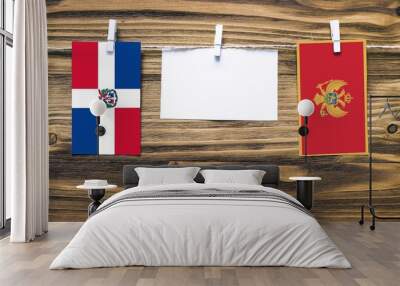 Hanging flags of Dominican Republic and Montenegro attached to rope with clothes pins with copy space on white note paper on wooden background.Diplomatic relations between countries. Wall mural