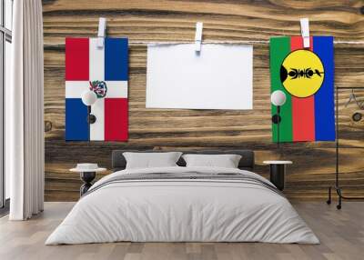 Hanging flags of Dominican Republic and New Caledonia attached to rope with clothes pins with copy space on white note paper on wooden background.Diplomatic relations between countries. Wall mural