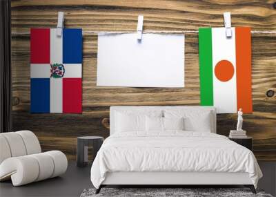 Hanging flags of Dominican Republic and Niger attached to rope with clothes pins with copy space on white note paper on wooden background.Diplomatic relations between countries. Wall mural