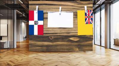 Hanging flags of Dominican Republic and Niue attached to rope with clothes pins with copy space on white note paper on wooden background.Diplomatic relations between countries. Wall mural