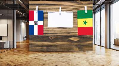 Hanging flags of Dominican Republic and Senegal attached to rope with clothes pins with copy space on white note paper on wooden background.Diplomatic relations between countries. Wall mural