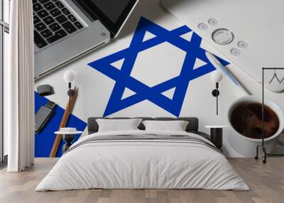 Israel national flag on top view work space of creative designer with laptop, computer keyboard, usb drive, graphic tablet, coffee cup, mouse on wooden table. Wall mural