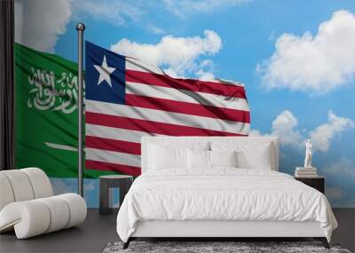 Saudi Arabia and Liberia flag waving in the wind against white cloudy blue sky together. Diplomacy concept, international relations. Wall mural