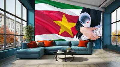 Surinamese Architect woman holding blueprint against Suriname waving flag background. Construction and architecture concept. Wall mural