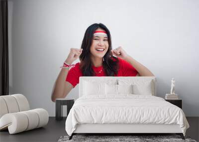 A happy young girl with the concept of Indonesian independence wearing a red t-shirt feels the spirit with the movement of clenching her fists Wall mural