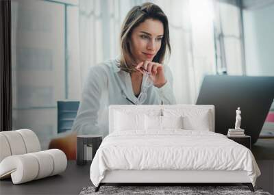 Confident businesswoman working on laptop at her workplace at modern office.Blurred background Wall mural