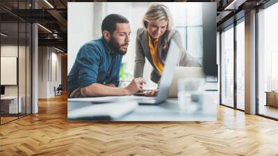 Coworkers team at work. Group of young business people in trendy casual wear working together in creative office. Wall mural